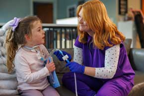 Nurse attaching tracheostomy tube for a young girl